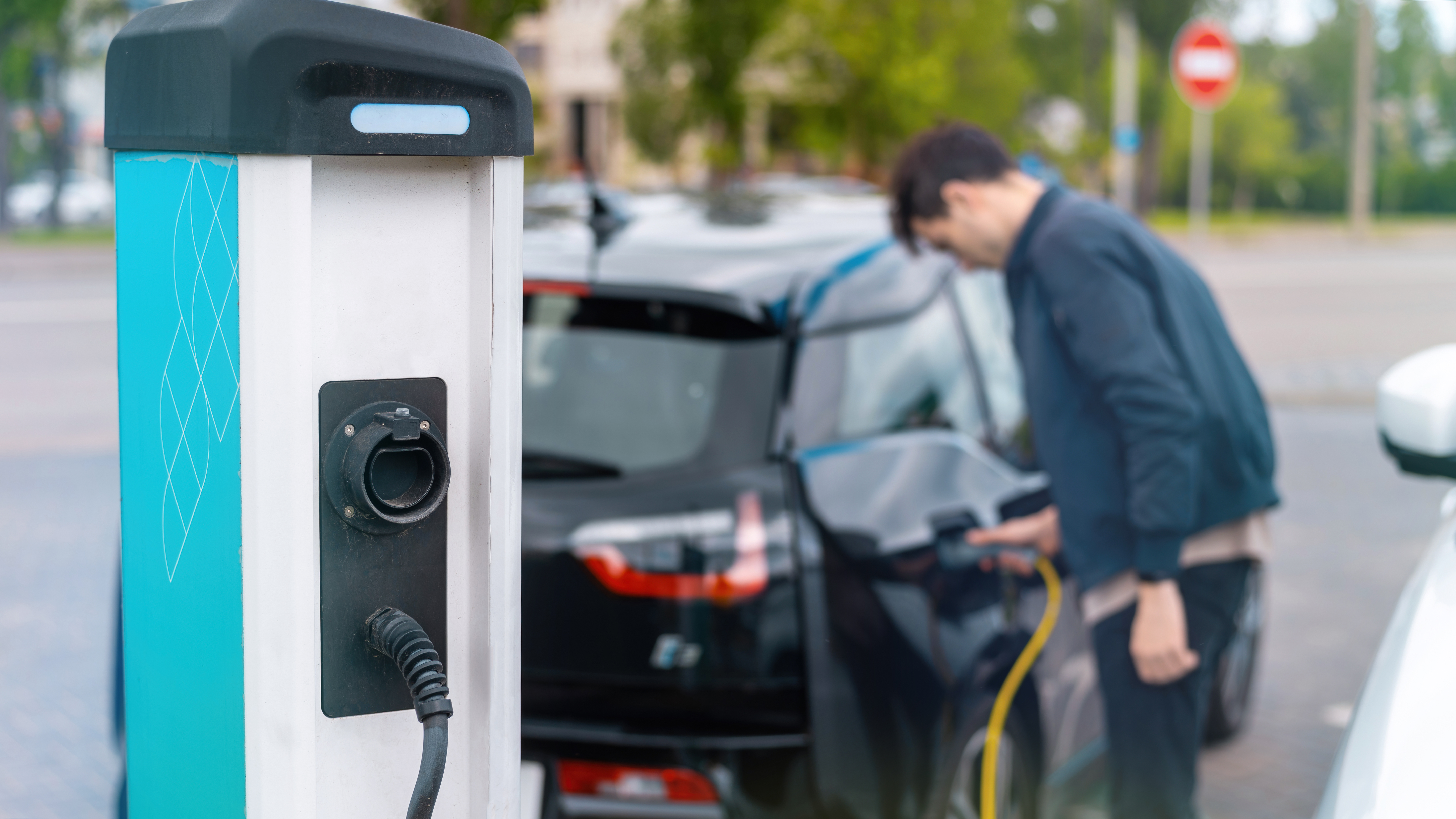 man-plugging-charger-into-electric-car-charge-station.jpg